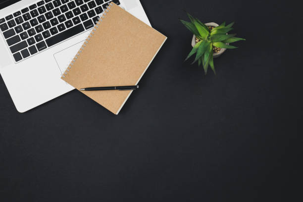 laptop, notepad and a office plant on a black background isolated, top view. - spiral notebook imagens e fotografias de stock