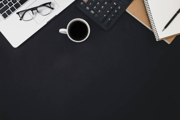 istock Flat lay black background with laptop, coffee cup and calculator, top view. 1492558888