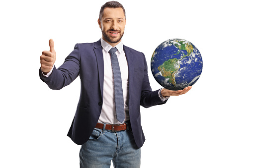 Young man holding the planet earth on his hand and gesturing thumbs up isolated on white background