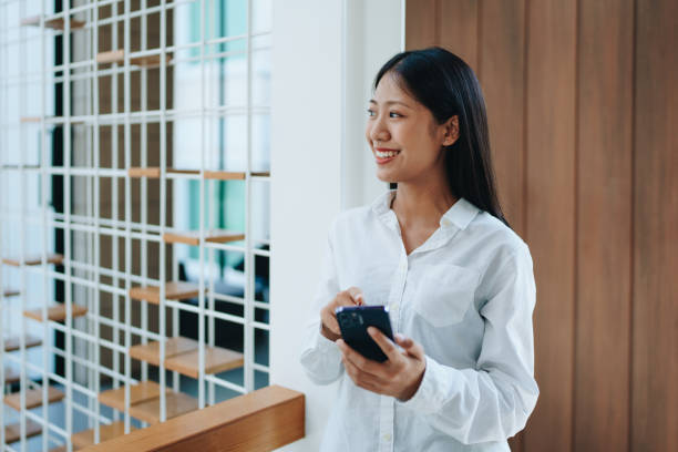 istock A young Asian self employed woman showing a smiling face and happiness while using smartphone mobile talking business and drinking coffee at a cafe shop. self-employed, freelance, relaxation. 1492559865