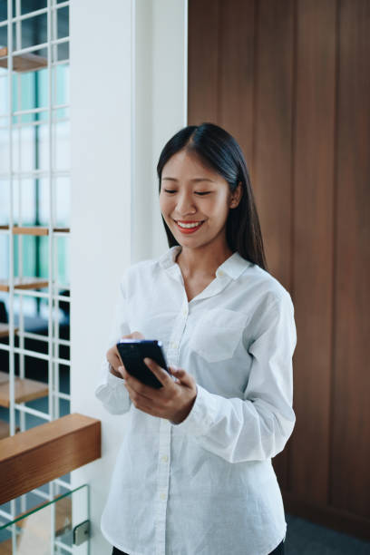 istock A young Asian self employed woman showing a smiling face and happiness while using smartphone mobile talking business and drinking coffee at a cafe shop. self-employed, freelance, relaxation. 1492559883