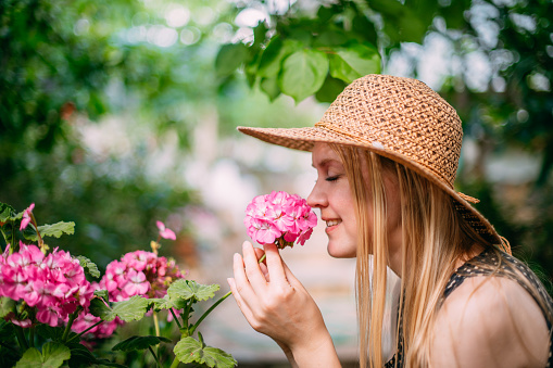 Child Girl Smelling Flowers in the Garden in Summer Season