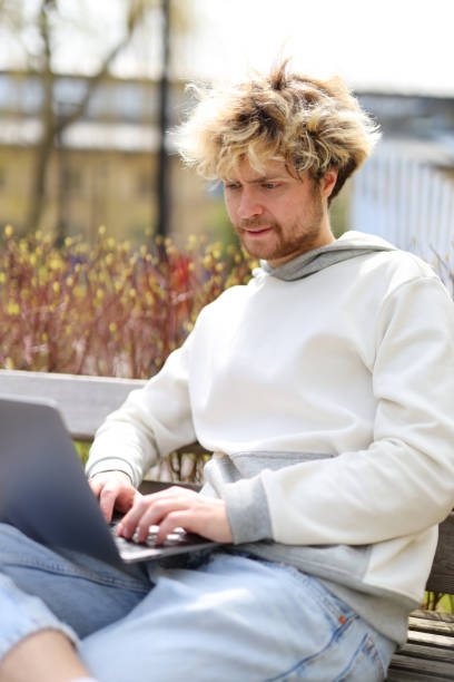 istock A bearded man works in a laptop on a park bench. 1492564383