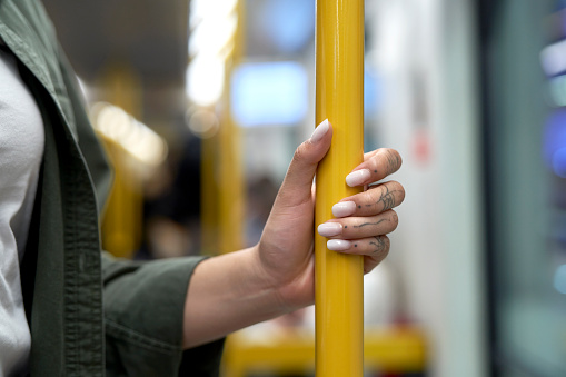 Hand of unrecognizable woman holding a handrail in the subway or train