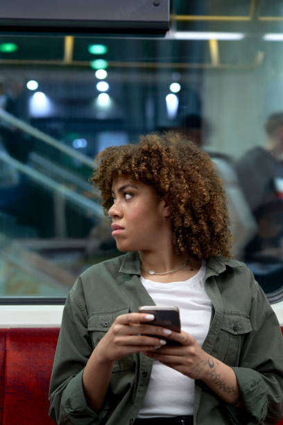 istock Young afro woman browsing a mobile phone in underground and looking away 1492564690