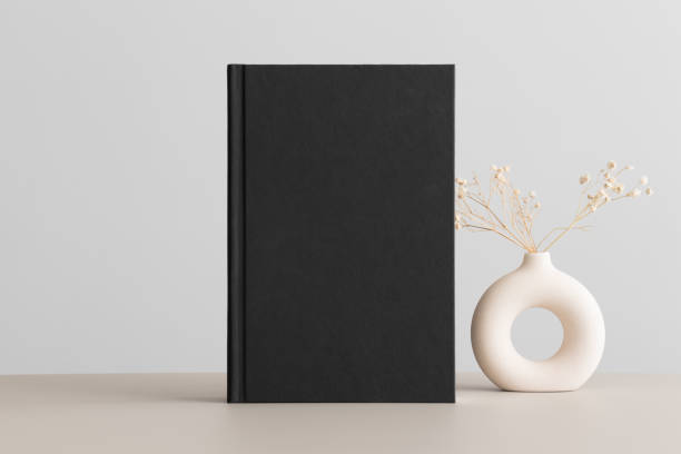 istock Black book mockup with a gypsophila decoration on the beige table. 1492565607