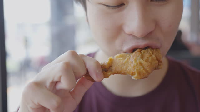 Asian boy eating chicken deliciously