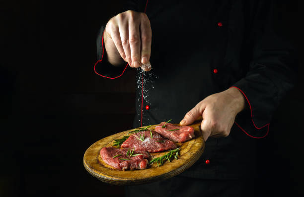 istock The chef salts raw beef steaks before barbecue. Preparation for roasting meat with rosemary and spices. Black space for restaurant recipe or menu 1492571273