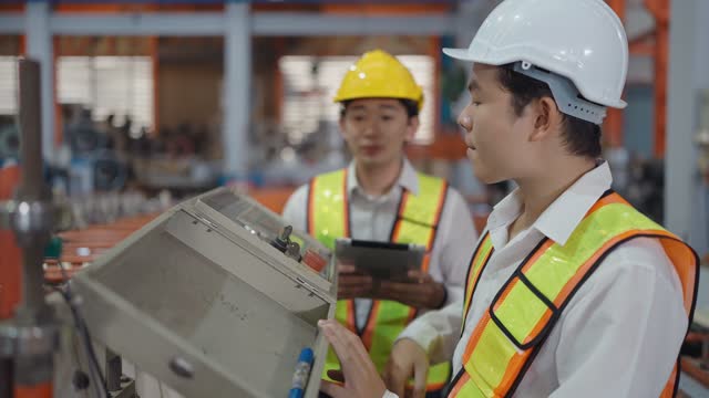 Two asian machine technicians inspect the electrical equipment in factory while working on tablet. Teamwork for successful in industrial business