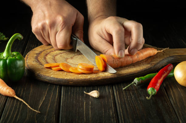 istock The chef cuts carrots into small pieces on a cutting board for preparing a vegetarian lunch or dinner. Set of vegetables on the kitchen table 1492573812