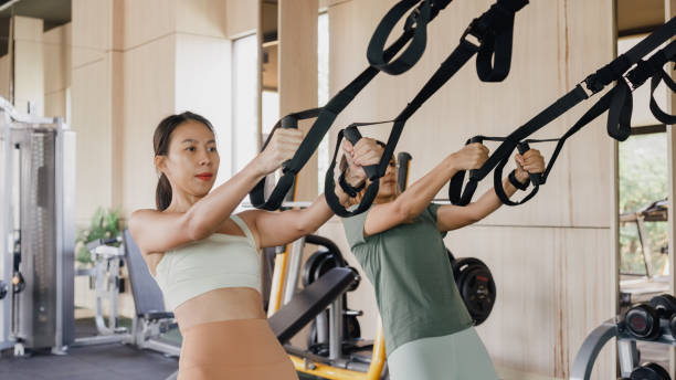 istock Young Asian athletic sports women exercise bodybuilder pulling down wire cable actively training in modern gym. Sports people workout. 1492576663