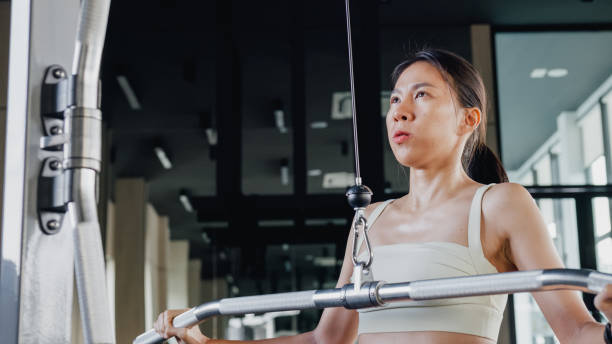 istock Young Asian athletic sports woman exercise bodybuilder pull-ups on a machine actively training in modern gym. Sports people workout. 1492576713