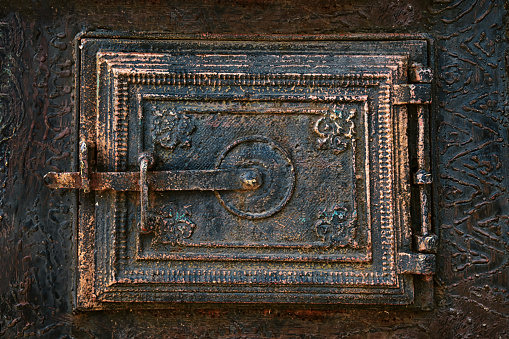 Close-up of a decorative cast-iron fireplace door in an old house.