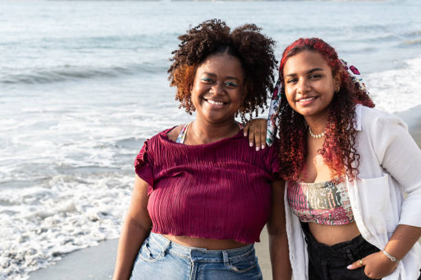 istock positive young friends smiling and looking at camera while standing on tropical beach 1492577304
