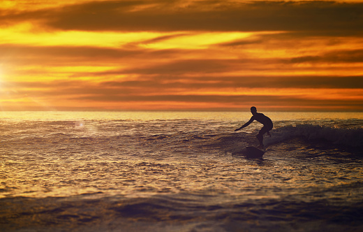 Balance, surf and sunset with a man on the beach during summer for travel, vacation or recreation. Sky, mockup and surfing with a male surfer in the ocean for a water sports hobby outdoor in nature