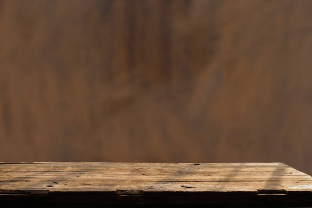 istock Empty wooden board on table top and blur inside over stucco wall blur background, mock up for display of goods. 1492582319