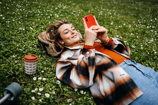 Beautiful woman lying on the grass and making selfie