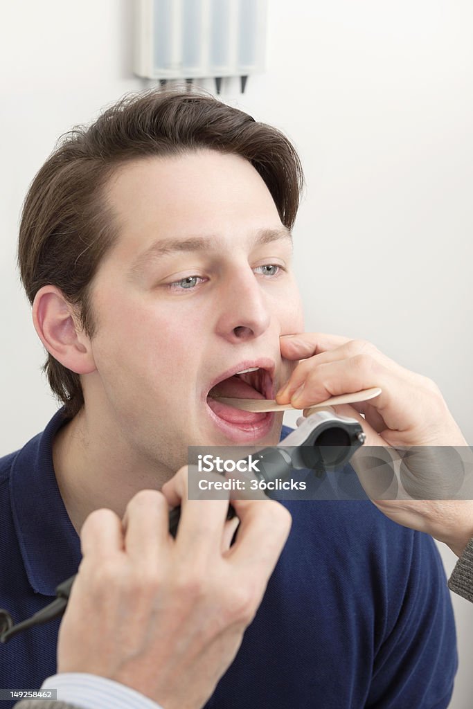 Examining Infection In the Mouth Young male patient getting his tongue and mouth checked for infection by doctor 20-29 Years Stock Photo