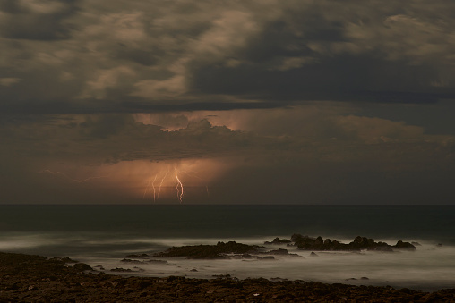 Storm, lightning and ocean with sky and weather for nature, danger and seascape at dusk. Dark, moody and cloudy with sunset horizon on coastline for winter climate, thunder and rain mockup