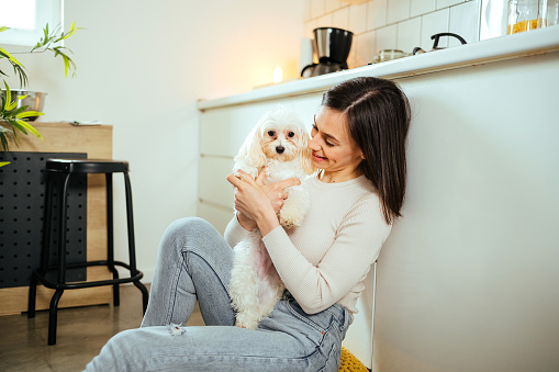 Woman sits in the kitchen at home with her dog