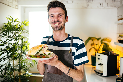 Portrait of a man holding a plate with a sandwich