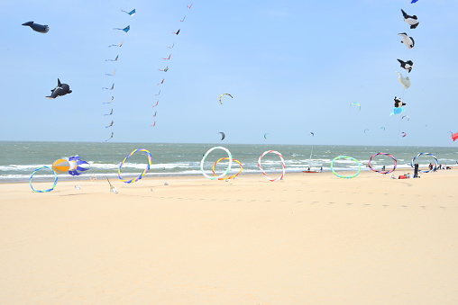 De Haan, West-Flanders, Belgium - May 21, 2023: inflatable cars, many flying kites in the air above the beach sand