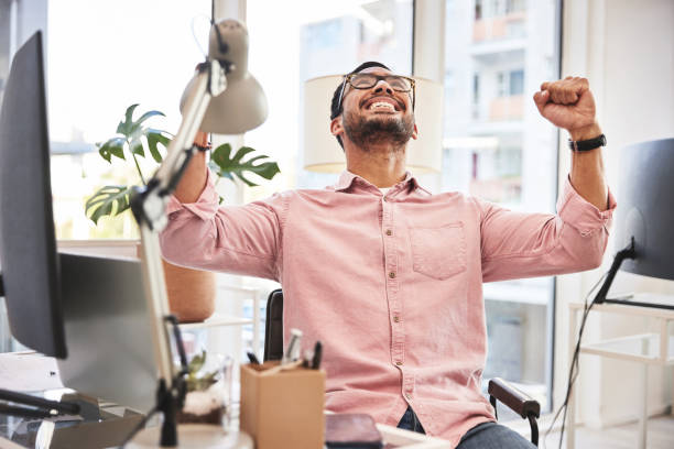 pugno, realizzazione e uomo che celebra il successo o l'obiettivo aziendale dopo aver ricevuto buone notizie in una startup. operaio maschio, eccitato e vincente in un ufficio - real people enjoyment happiness confidence foto e immagini stock