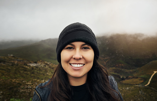 Woman, smile and portrait for travel outdoor in nature while happy about adventure, holiday or vacation. Face of a female person out hiking on mountain or countryside for peace, wellness and freedom