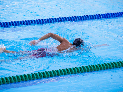 Female swimmer on evening training on swimming pool, warming up, swimming  backstroke during training.
