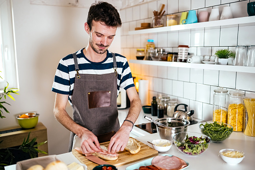 Man is preparing a delicious sandwich in the kitchen