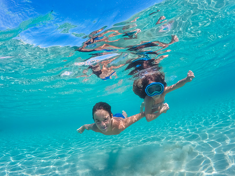 Children having fun diving underwater on their summer vacation