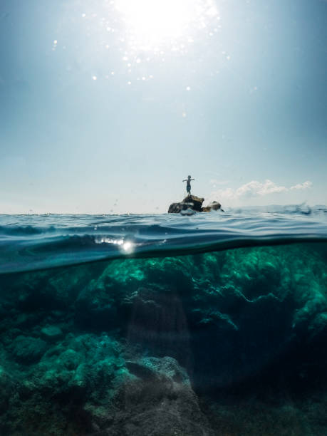 istock Boy standing and resting on a cliff in a beautiful crystal sea 1492597440