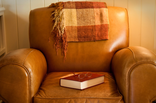 Comfy leather chair with red book and glasses, waiting for a reader