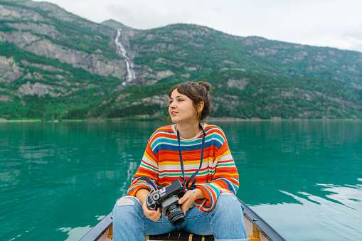 Young woman photographing while canoeing on the lake in Norway