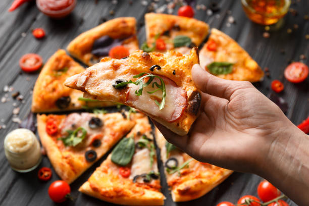istock The hand holds a slice of pizza, close-up. 1492599865