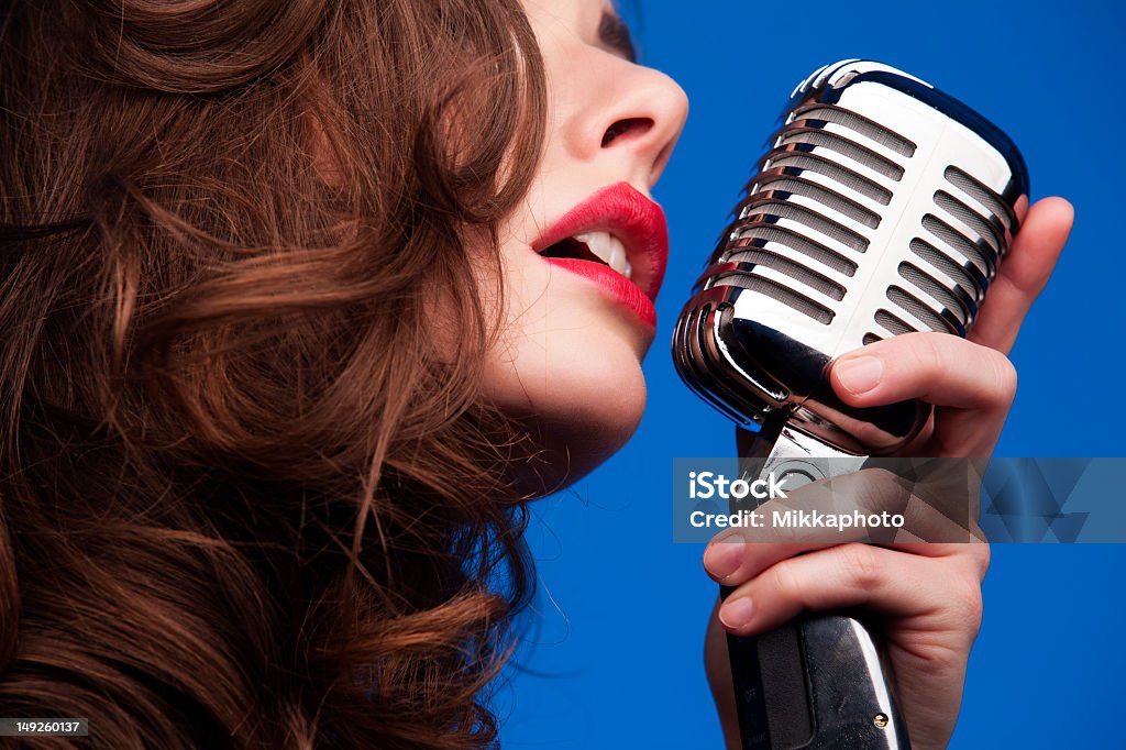 Woman with an old fashioned microphone Woman with a retro microphone singing, studio shot. Canon EOS 1Ds mkIII Females Stock Photo