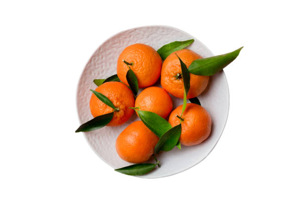 istock Fresh cutted clementines and whole mandarin over round plate isolated on white background. Food and drink ingredients preparing. healthy eating theme top view with copy space 1492605117