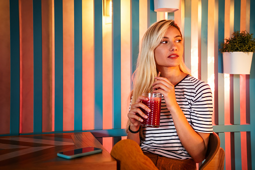 Portrait of a healthy young happy woman drinking a juice in cafe. People health lifestyle concept