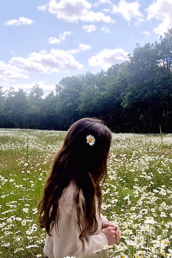 Little girl with long hair in a field of daisies