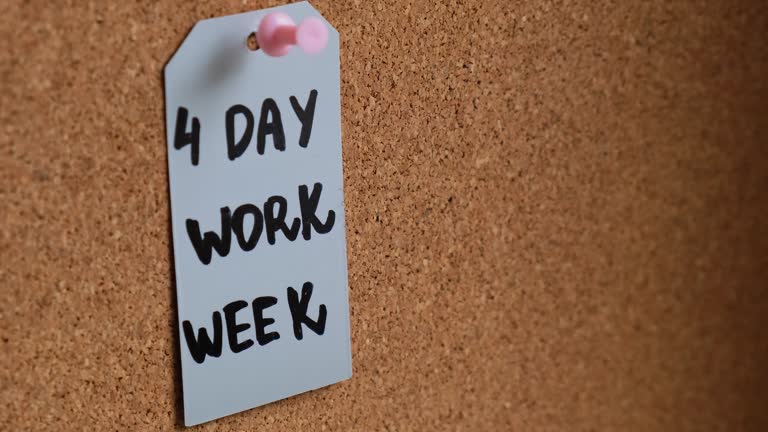 Hand pin note 4 day work week text on paper note pinned to desk four day working week concept. Modern approach doing business short workweek. Effectiveness of employees. Productivity and efficiency
