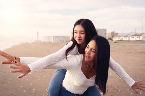 retrato madre e hija latinas a cuestas disfrutando juntas del atardecer en la playa - región de coquimbo fotografías e imágenes de stock