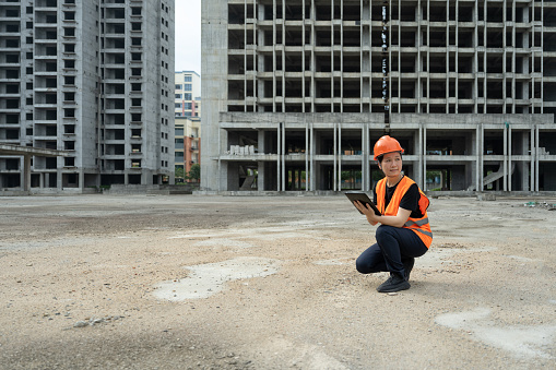 An Asian female engineer works on a tablet computer at a newly built commercial building site