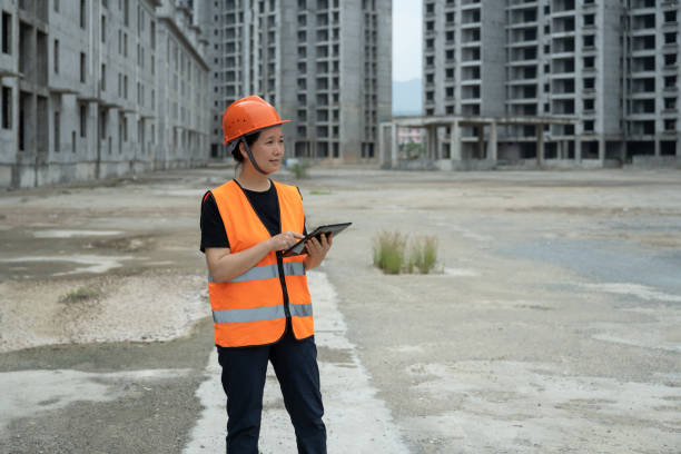 una ingeniera trabaja en una tableta en una obra sin terminar - blueprint construction worker real estate new fotografías e imágenes de stock