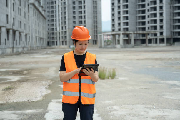 una ingeniera trabaja en una tableta en una obra sin terminar - blueprint construction worker real estate new fotografías e imágenes de stock