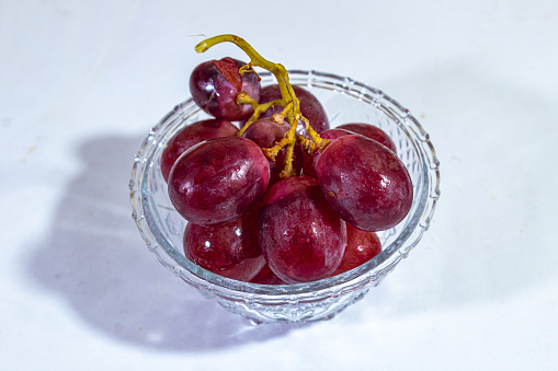 one glass tumbler, filled with a large red wine on a plain white background