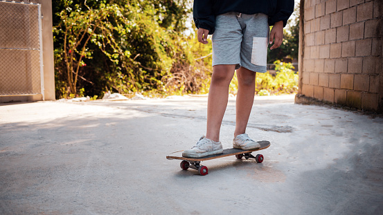 Close-up of a boy practicing standing on a skateboard with his dog.