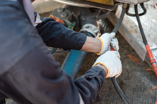 The technician worker is connecting the hydualic line with skimmer unit, the oil spill recovery machine. Industrial working action photo. selective focus.