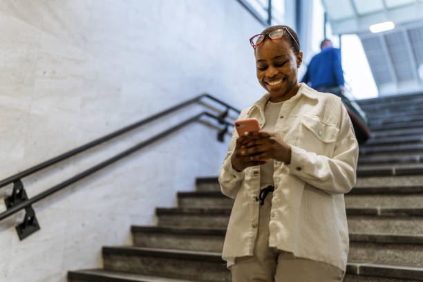 istock Young black woman with short afro hairstyle using mobile in the train station. 1492628954
