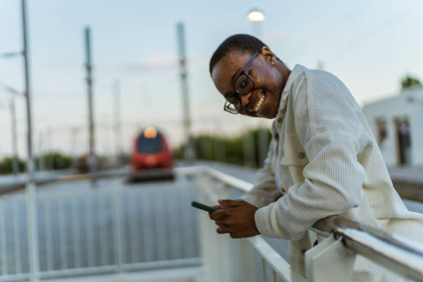 istock Smiling woman using smart phone on platform station. 1492629088