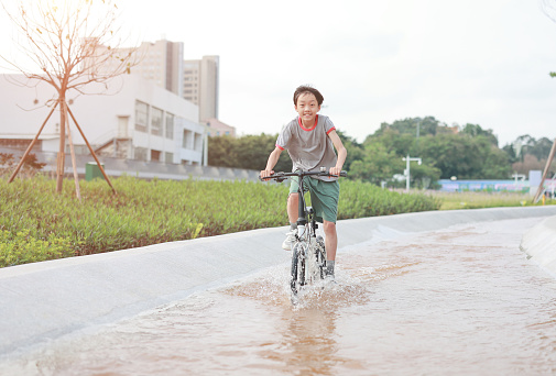Boy riding bike through puddle